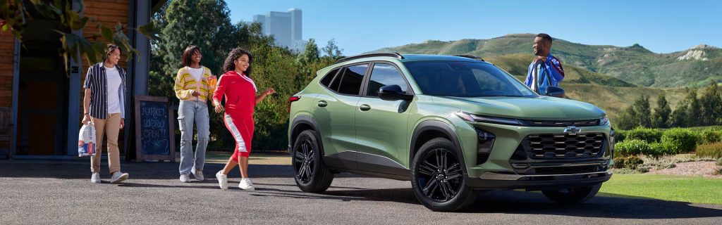 A green Chevrolet SUV parked outdoors with a group of four people walking towards it.