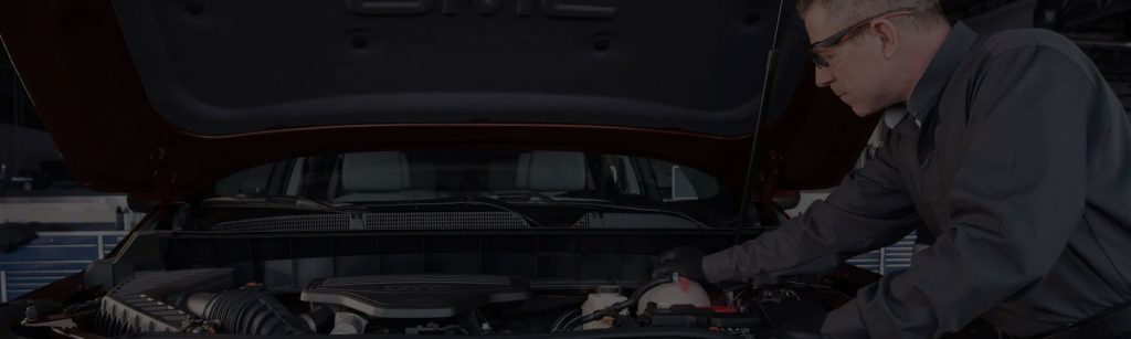 A mechanic inspecting the engine of a GMC vehicle.