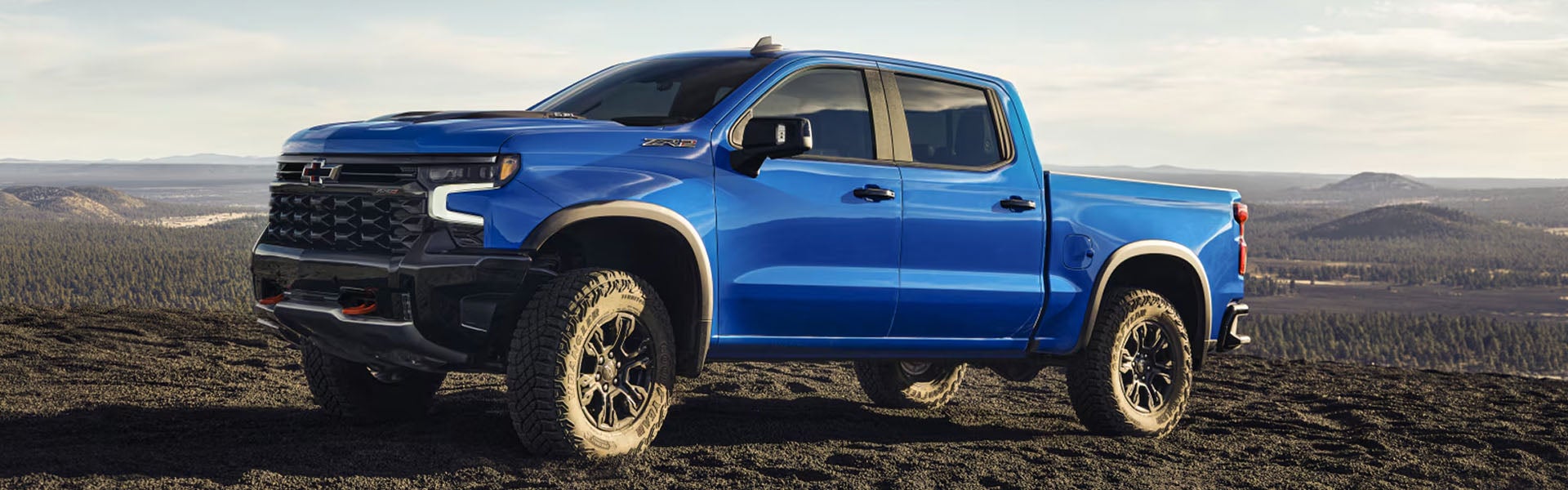 Blue Chevrolet Silverado pickup truck parked in a scenic landscape.