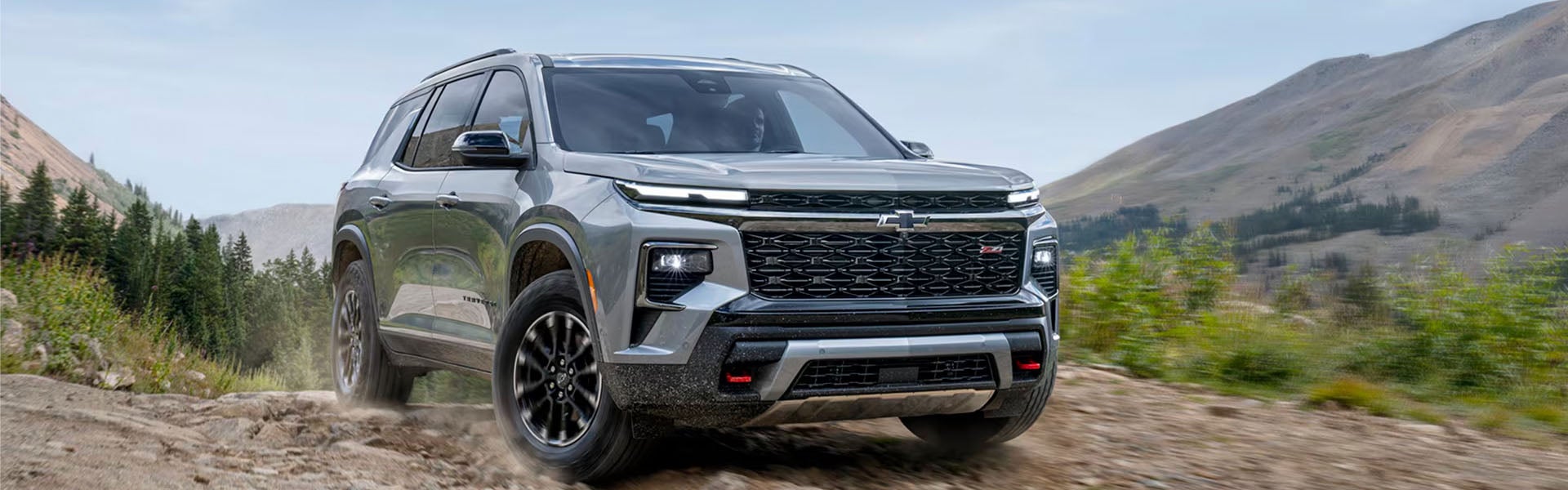Chevrolet SUV driving on a rugged mountain road surrounded by scenic outdoor landscapes.