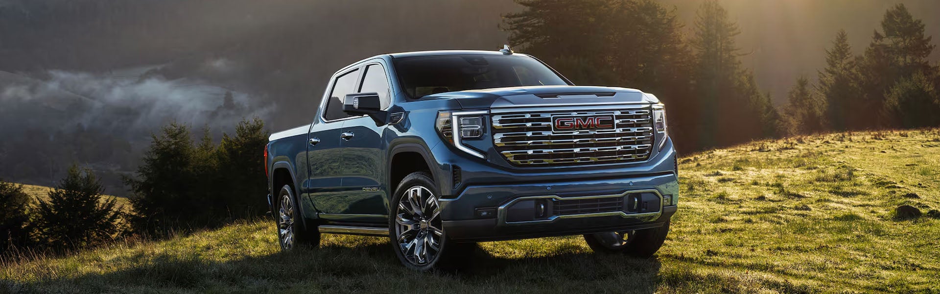 Blue GMC Sierra 1500 pickup truck parked in a scenic mountain landscape